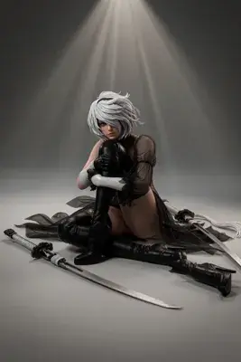 A cosplayer portrays 2B (YoRHa No.2 Type B) from NieR: Automata, sitting on the floor with a blindfold and katana under dramatic lighting.