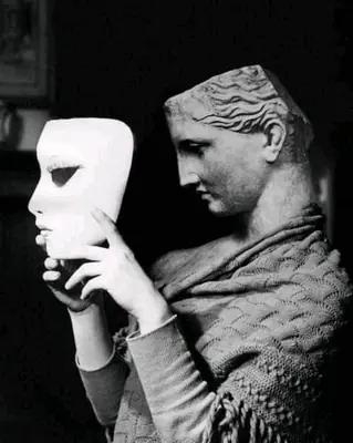 Black and white image of 2B from NieR: Automata depicted as a classical statue holding a mask, symbolizing identity and artificiality.
