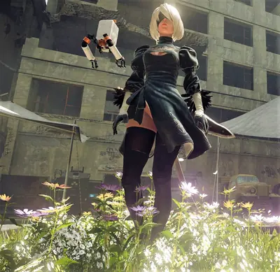 2B (YoRHa No.2 Type B) from NieR: Automata stands in a post-apocalyptic setting with overgrown flowers and ruins.