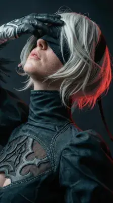 Cosplayer as 2B from NieR:Automata, wearing the character's iconic blindfold and outfit.