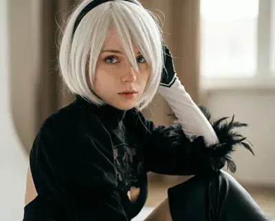 Cosplayer as 2B from NieR:Automata in her iconic black dress and white gloves.