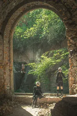 2B and 9S from Nier Automata cosplay photography showing android warriors in signature outfits within a ruined stone archway